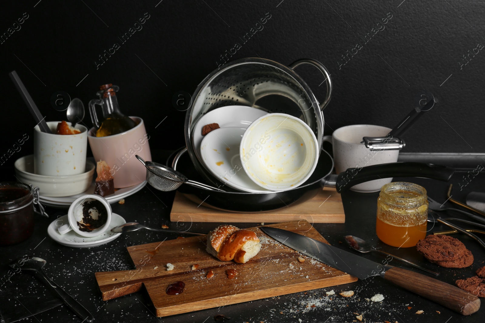 Photo of Many dirty utensils, dishware and food leftovers on black countertop. Mess in kitchen