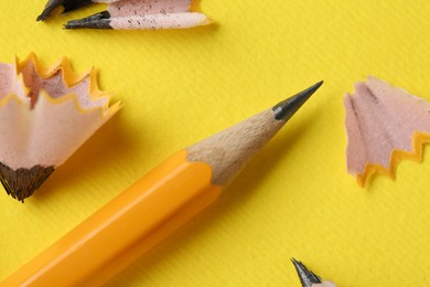 Graphite pencil and shavings on yellow background, top view. Macro photo