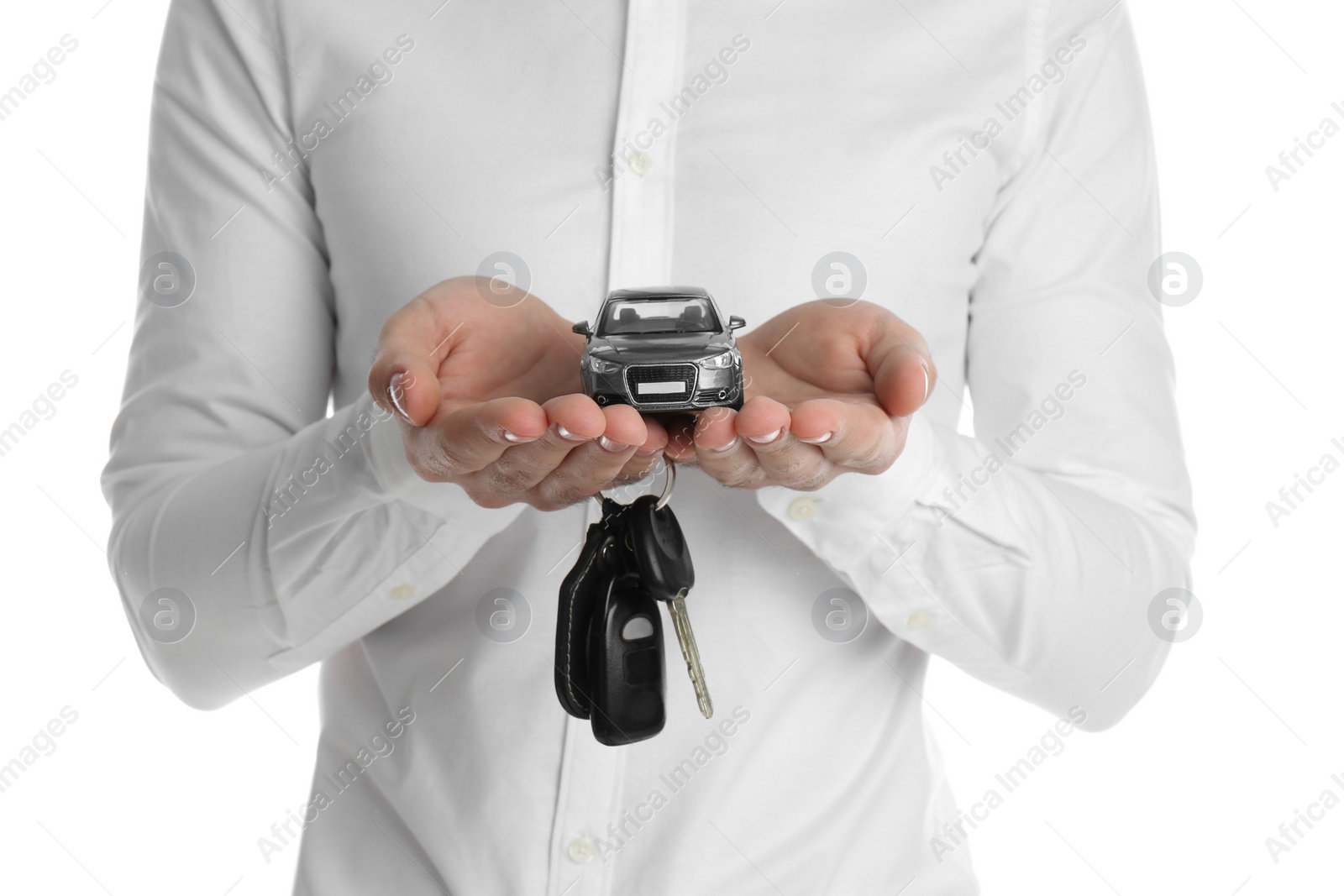 Photo of Man holding key and miniature automobile model on white background, closeup. Car buying