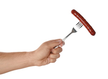 Photo of Man holding fork with grilled sausage on white background, closeup. Barbecue food