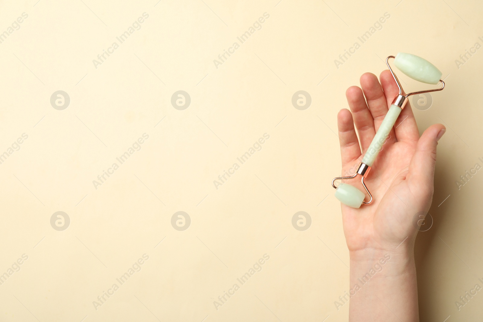 Photo of Woman with natural face roller on beige background, top view. Space for text
