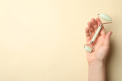 Woman with natural face roller on beige background, top view. Space for text