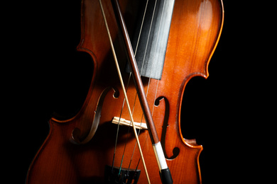 Photo of Classic violin and bow on black background, closeup