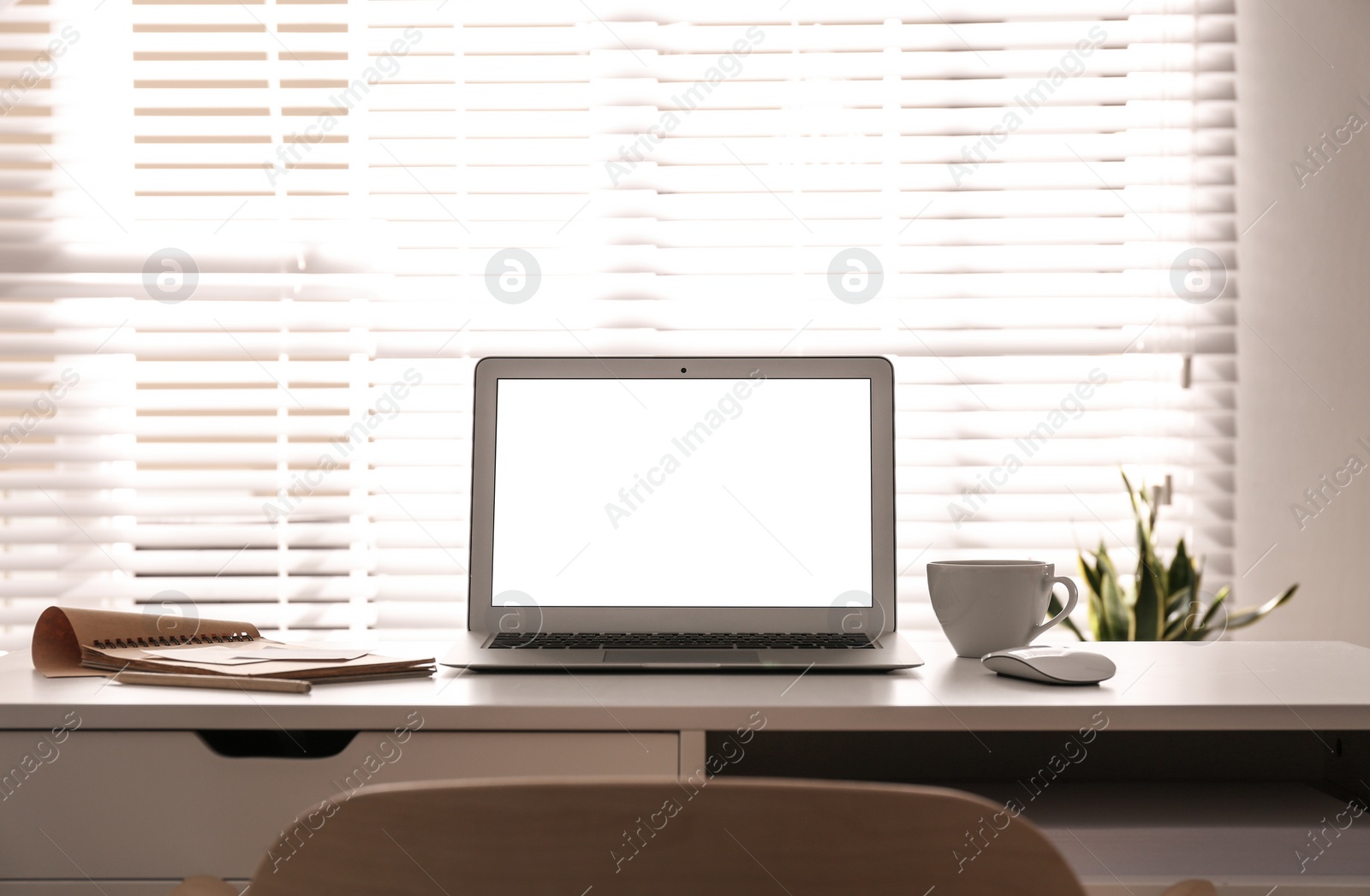 Photo of Laptop on desk near window in office. Comfortable workplace