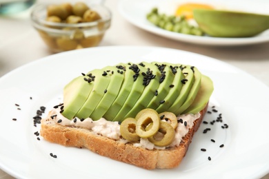 Photo of Crisp toast with avocado, cream cheese and olives on plate, closeup