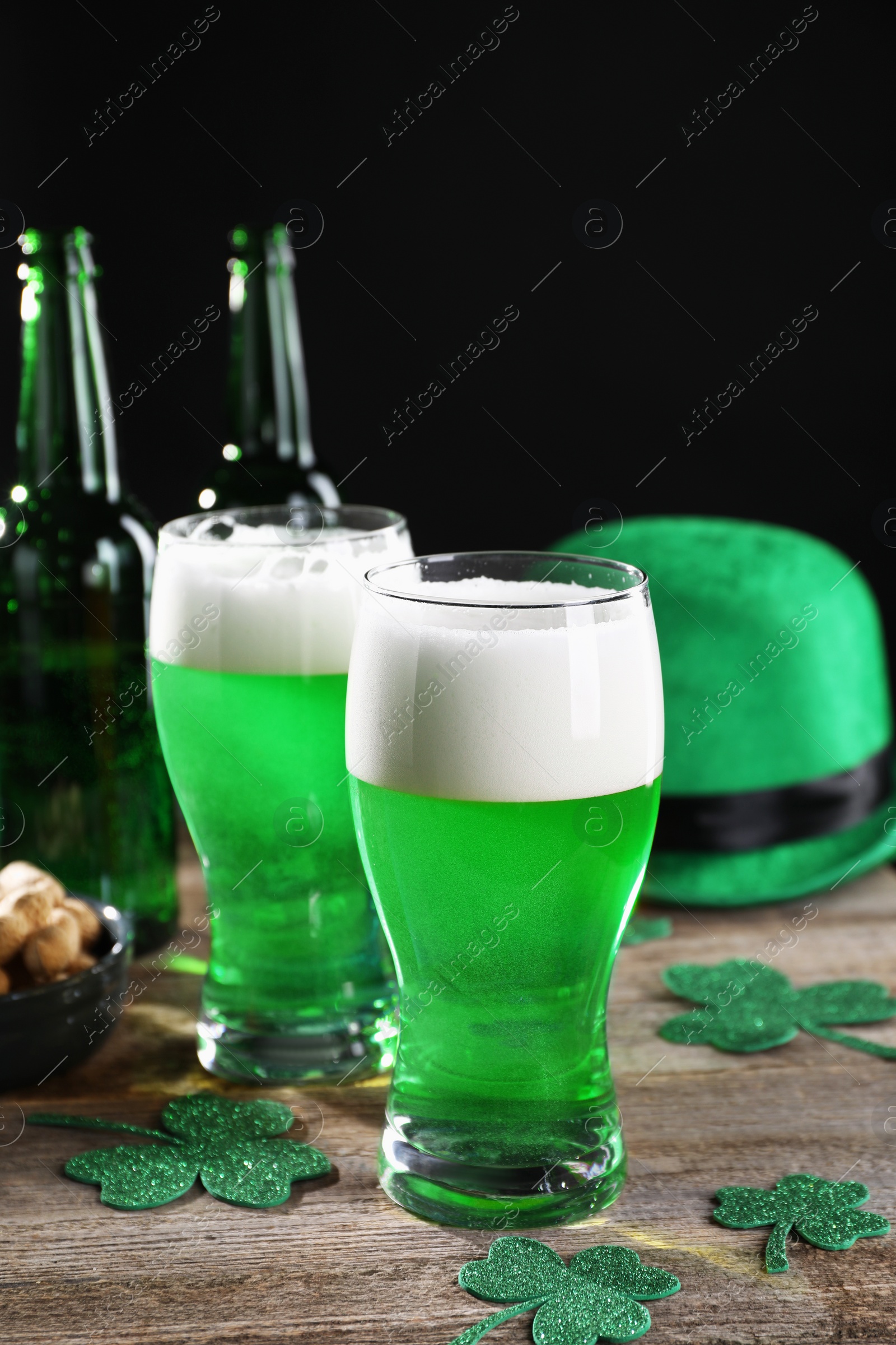 Photo of St. Patrick's day party. Green beer, nuts, leprechaun hat and decorative clover leaves on wooden table