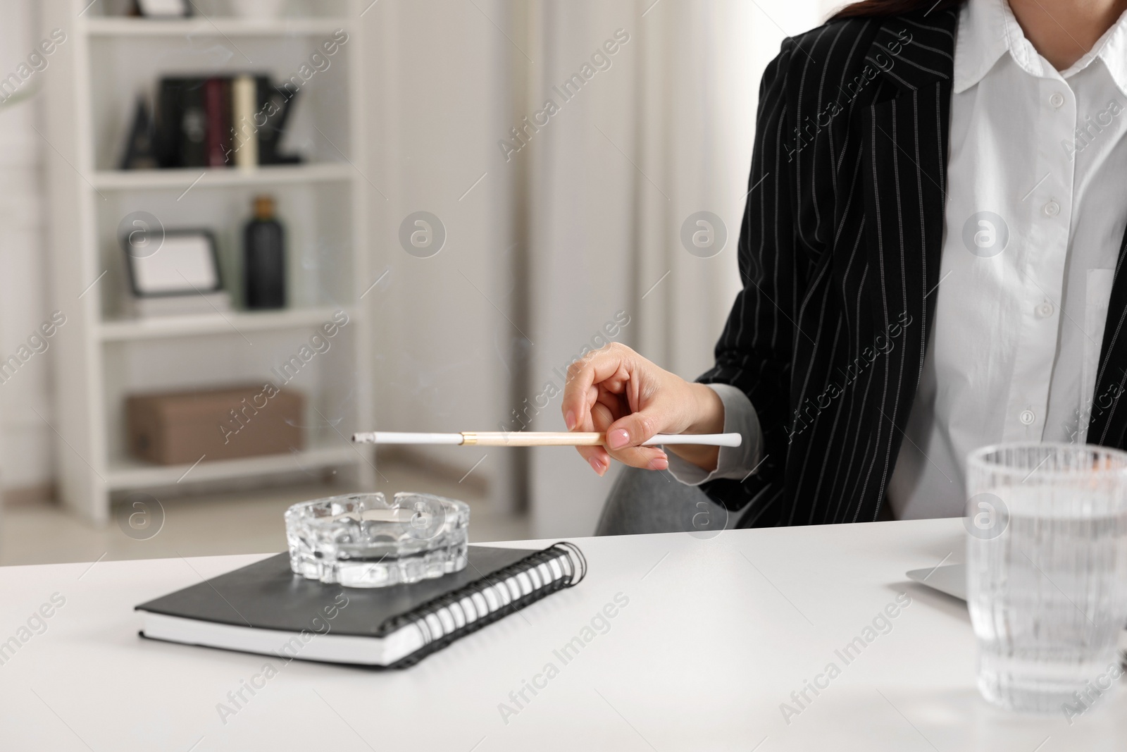 Photo of Woman using long cigarette holder for smoking at workplace in office, closeup