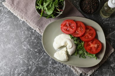 Photo of Delicious burrata cheese with tomatoes and arugula on grey table, flat lay. Space for text