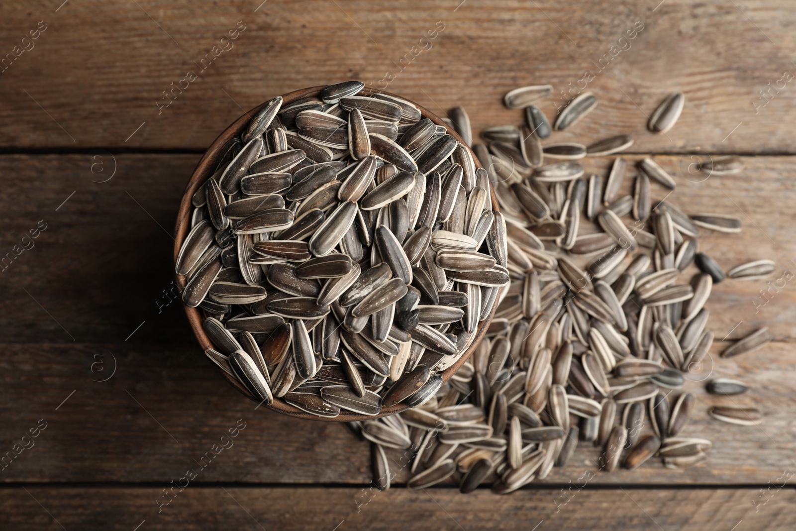 Photo of Raw sunflower seeds on wooden table, flat lay