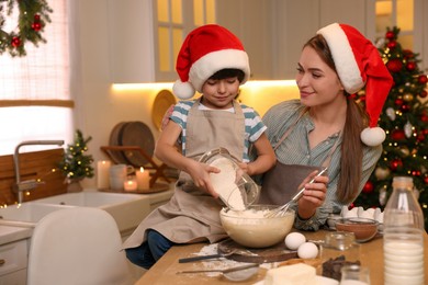 Photo of Mother with her cute little son making dough for Christmas cookies in kitchen