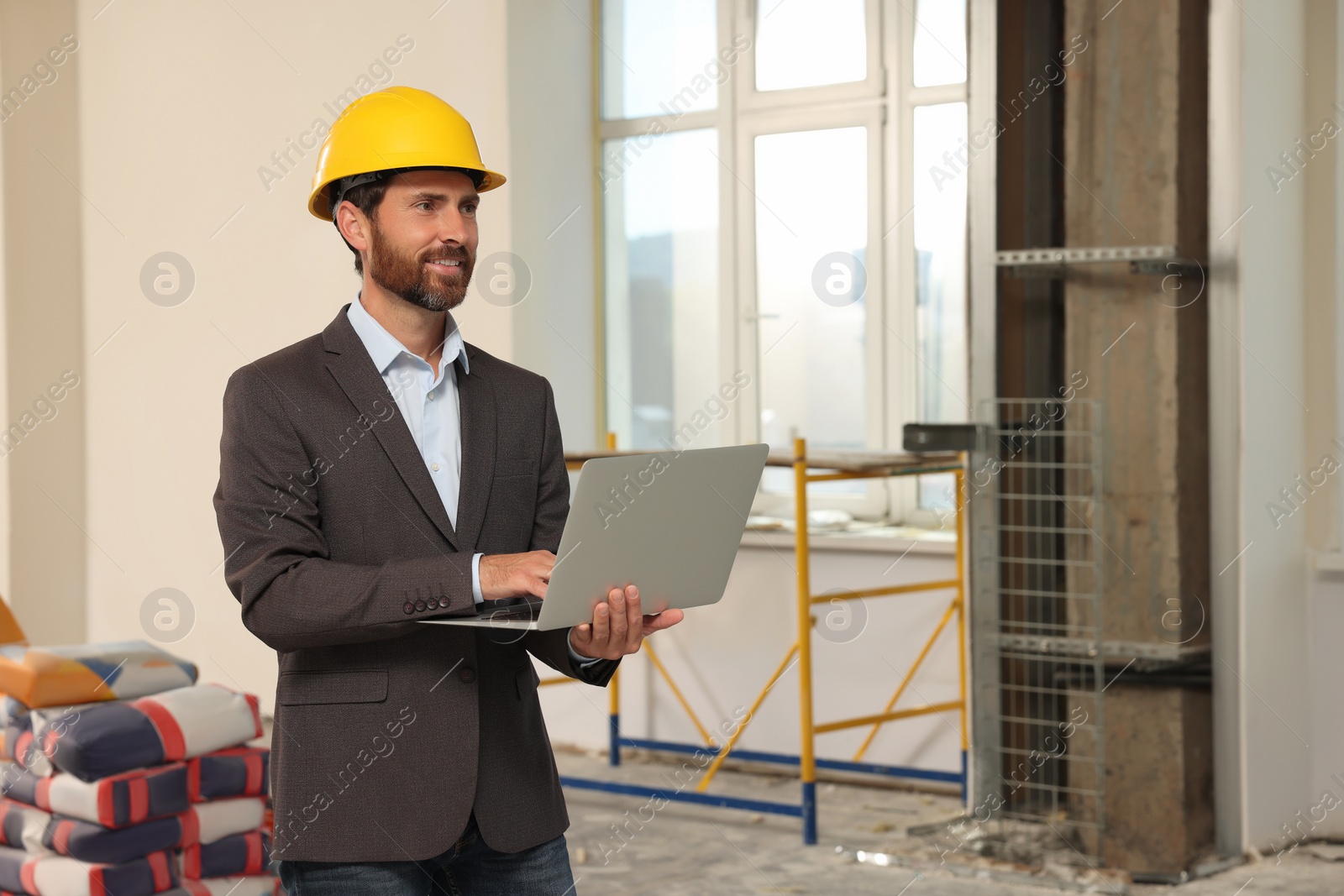 Photo of Professional engineer in hard hat with laptop indoors