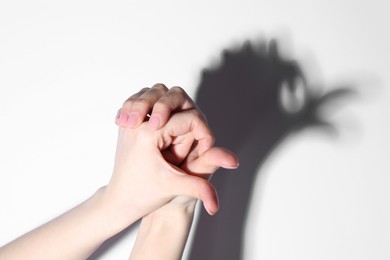 Photo of Shadow puppet. Woman making hand gesture like bird on light background, closeup