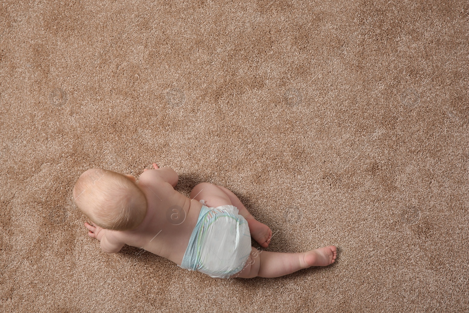 Photo of Cute little baby crawling on carpet indoors, top view with space for text