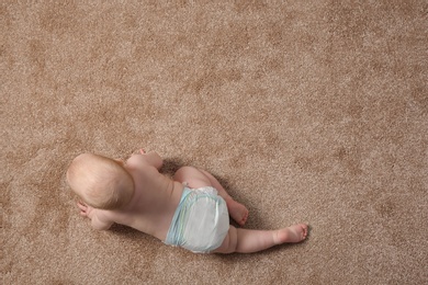 Photo of Cute little baby crawling on carpet indoors, top view with space for text