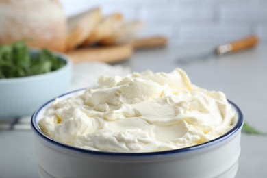 Bowl of tasty cream cheese on grey table, closeup