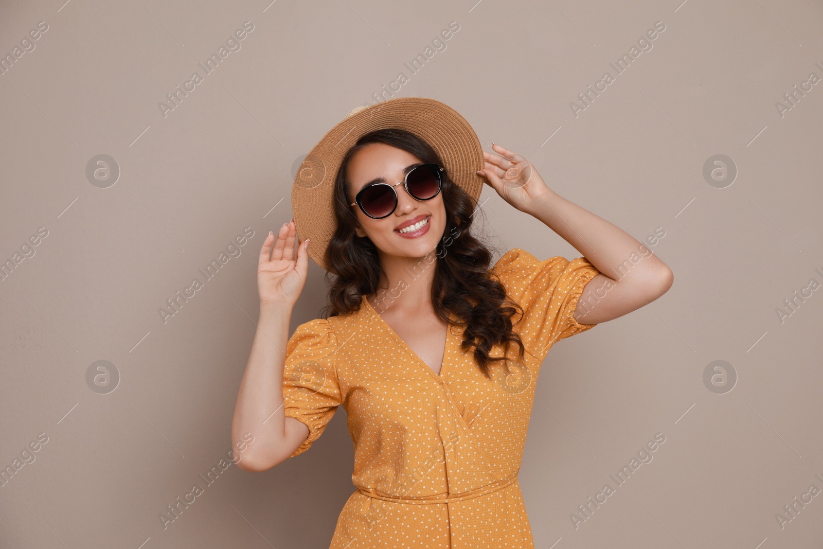Photo of Beautiful young woman with straw hat and stylish sunglasses on beige background