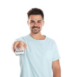 Happy young man operating air conditioner with remote control on white background