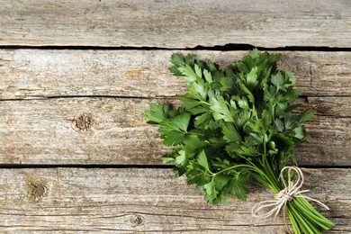 Photo of Bunch of fresh green parsley leaves on wooden table, top view. Space for text