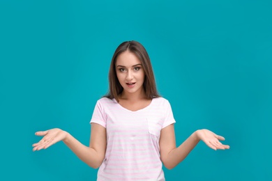 Emotional young woman in casual outfit on turquoise background
