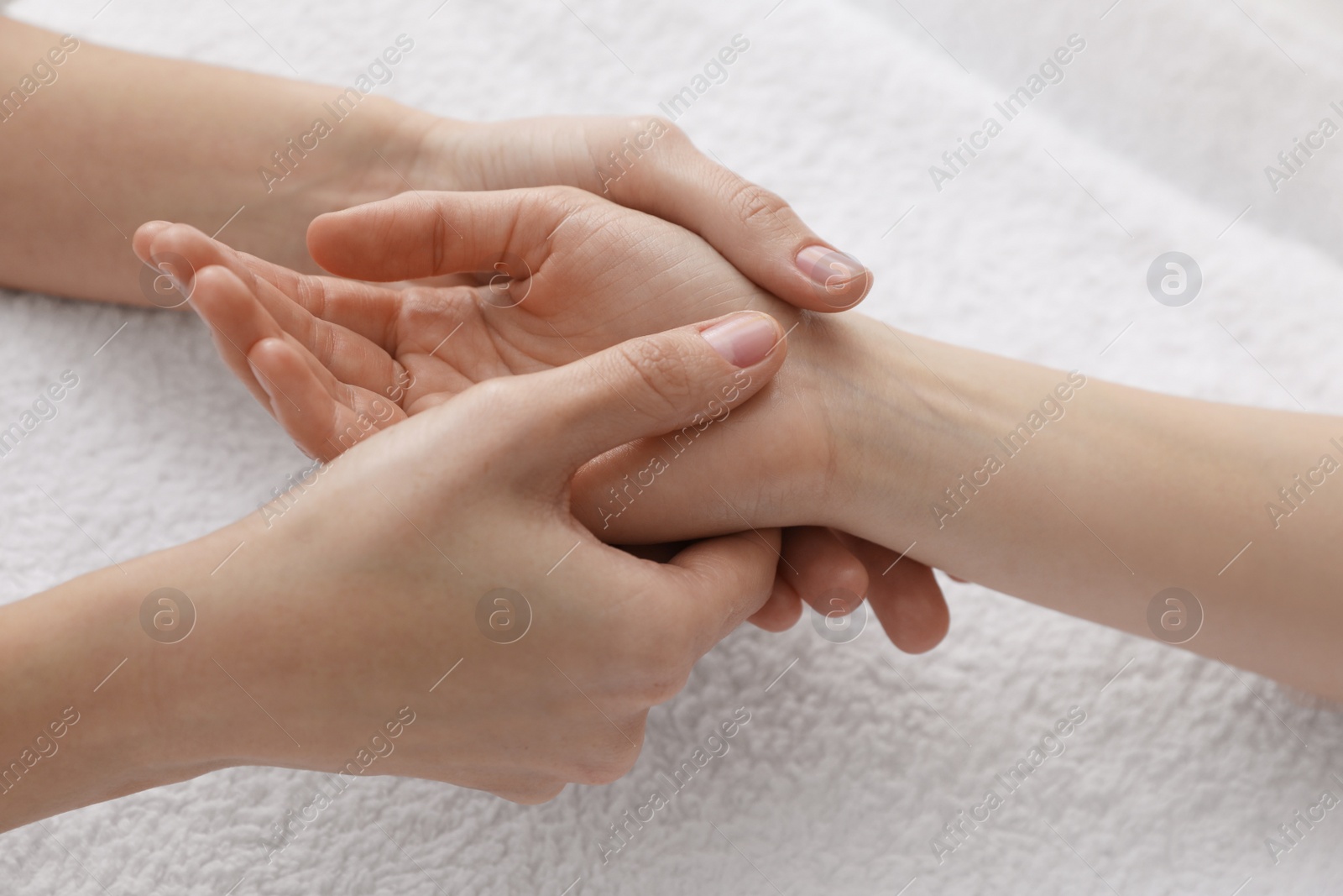 Photo of Woman receiving hand massage on soft towel, closeup