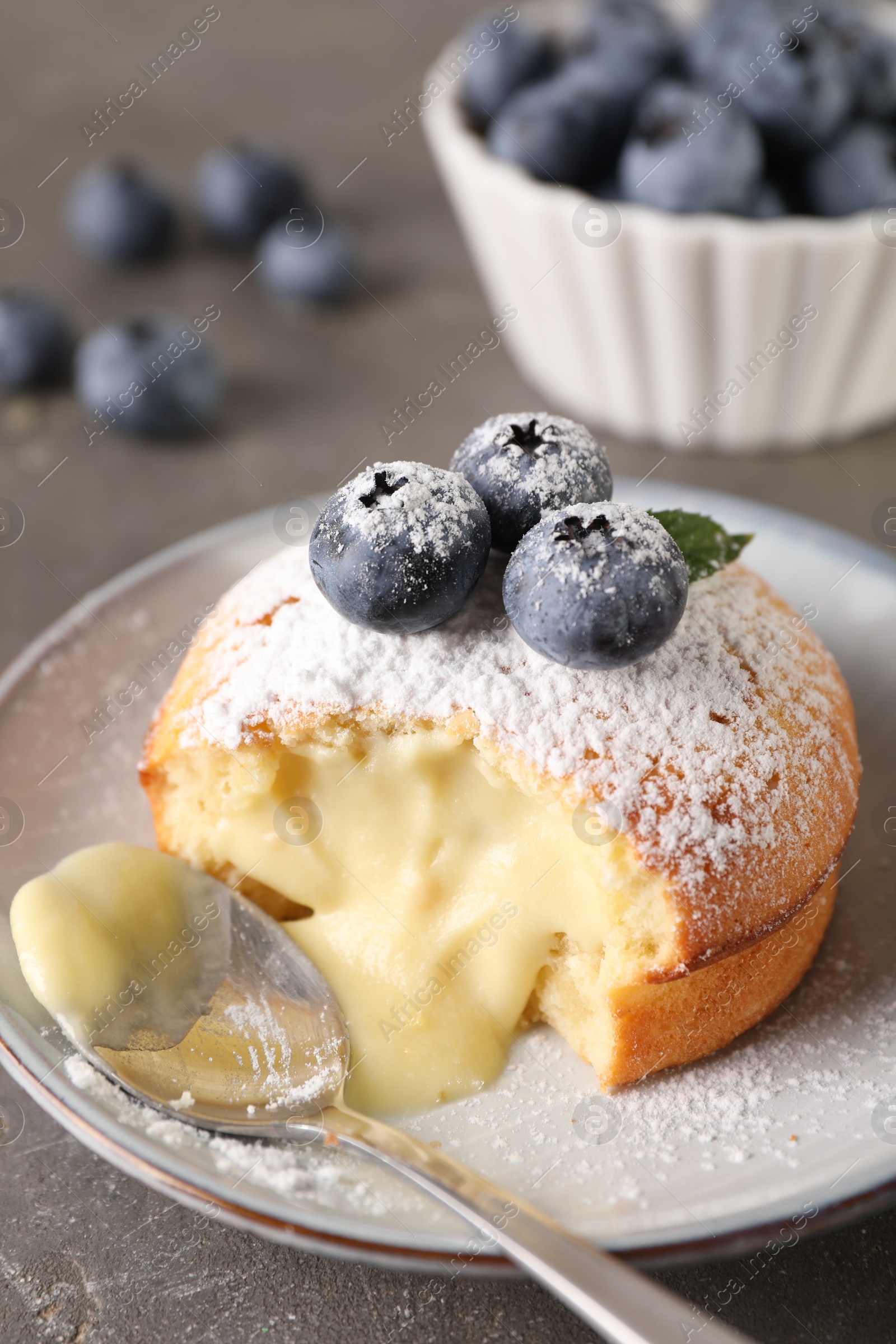 Photo of Tasty vanilla fondant with white chocolate and blueberries on grey table, closeup