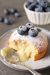 Tasty vanilla fondant with white chocolate and blueberries on grey table, closeup