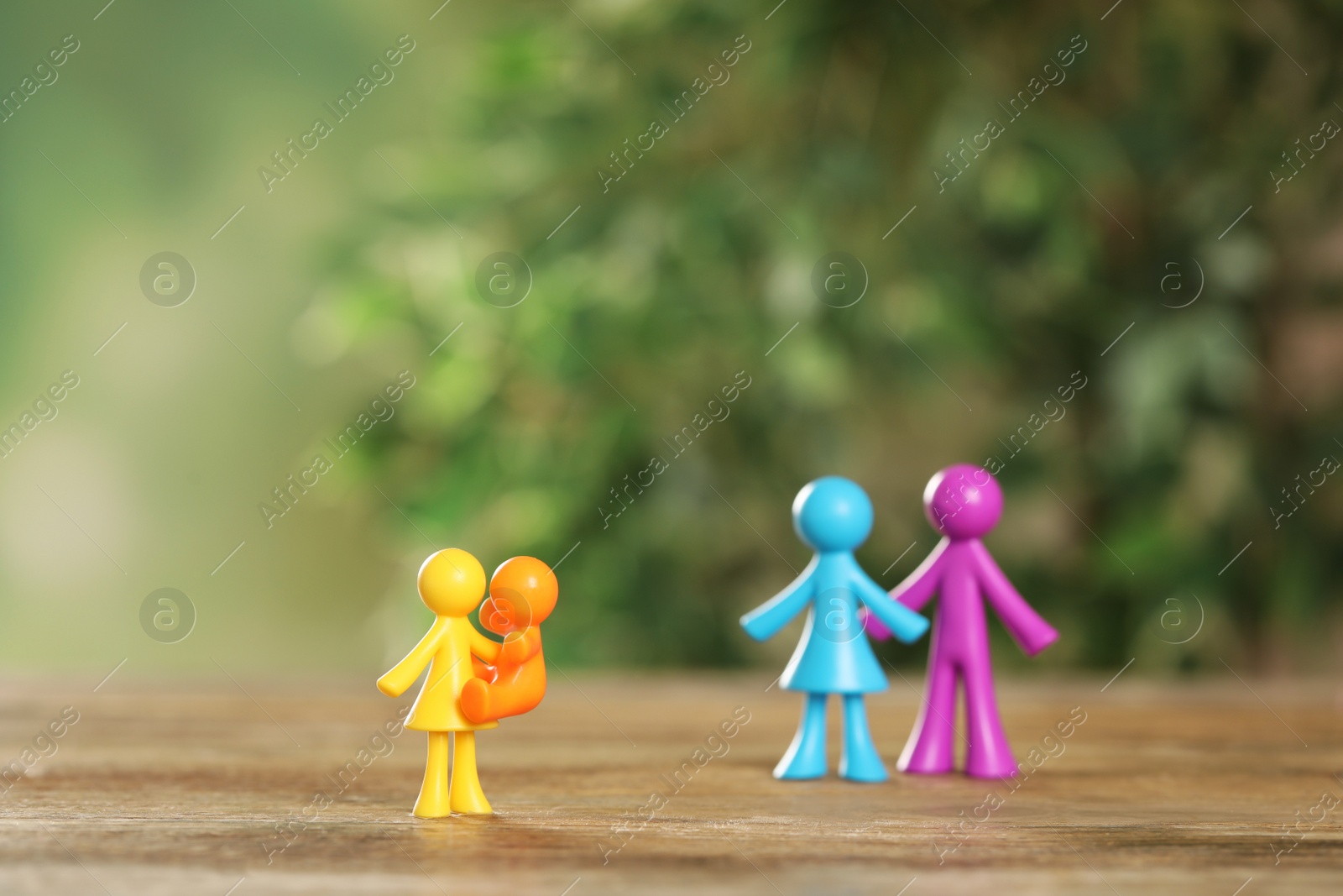 Photo of MYKOLAIV, UKRAINE - JANUARY 04, 2022: Colorful human figures on wooden table against blurred green background. Surrogacy concept