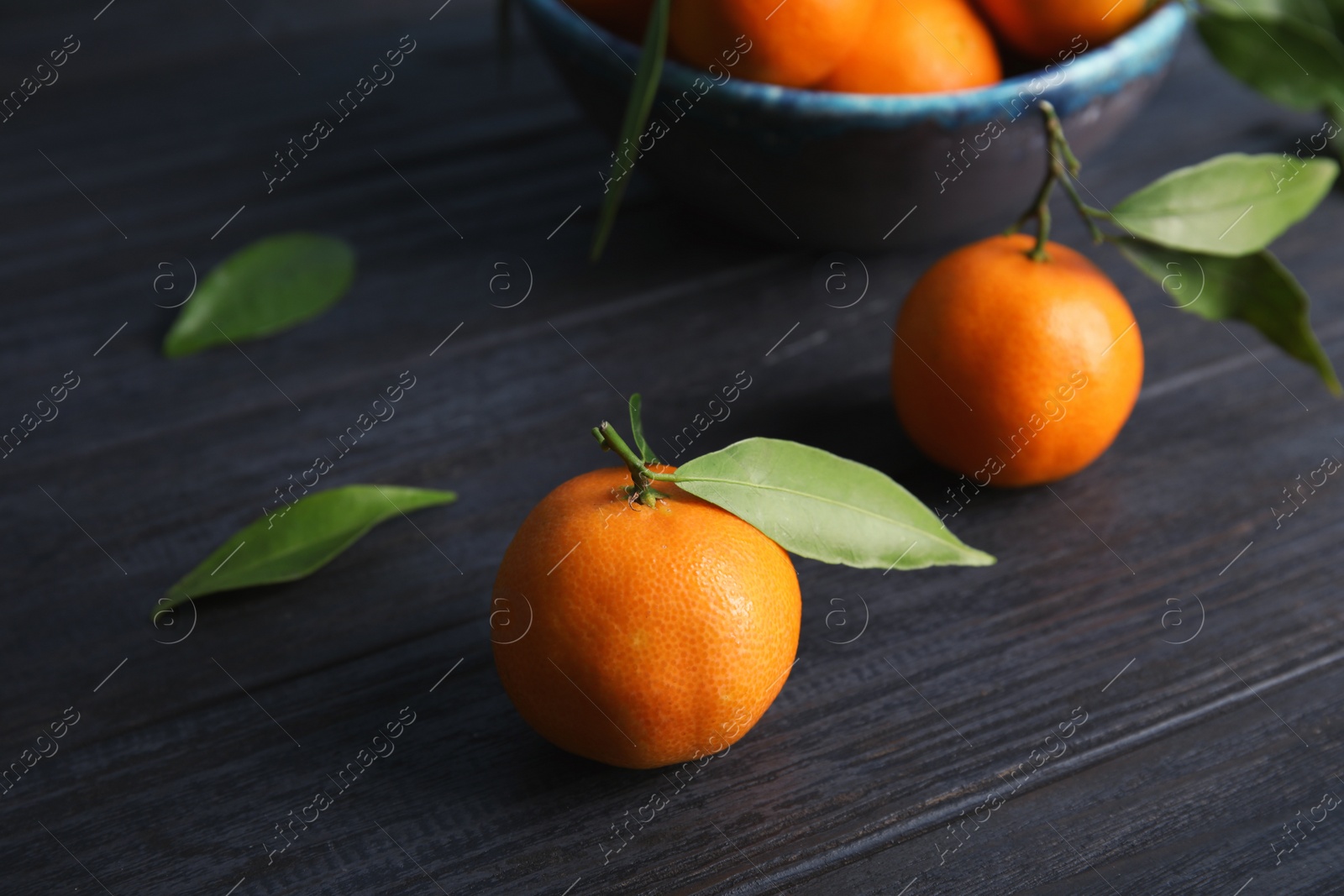 Photo of Fresh ripe tangerines with green leaves on table