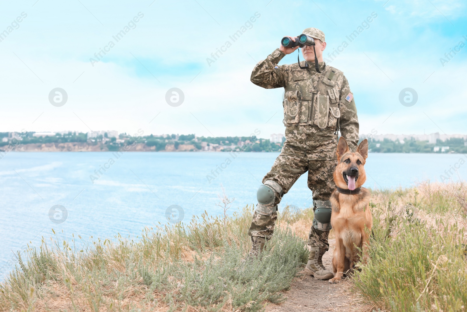 Photo of Man in military uniform with German shepherd dog near river