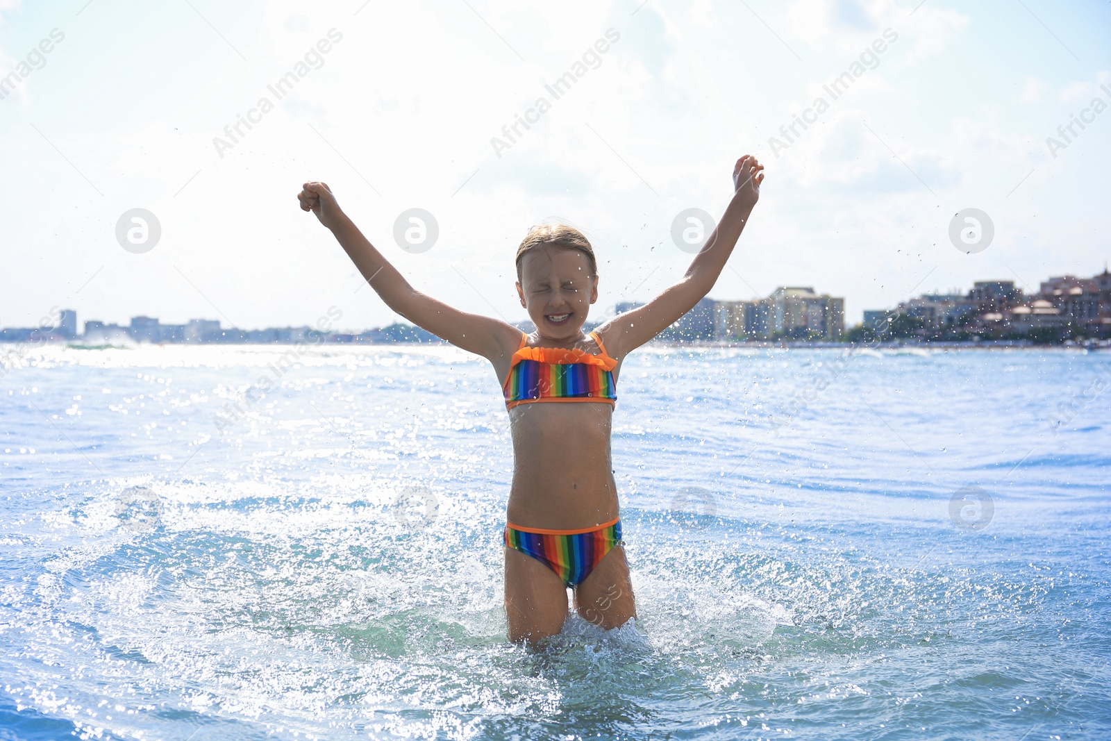 Photo of Happy little girl having fun in sea on sunny day. Beach holiday