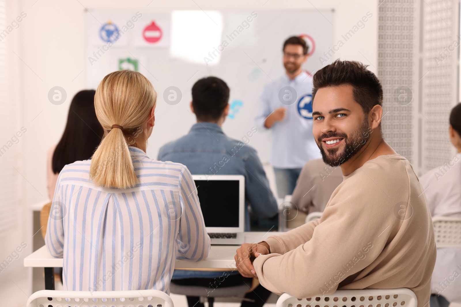 Photo of Happy man at desk in class during lesson in driving school