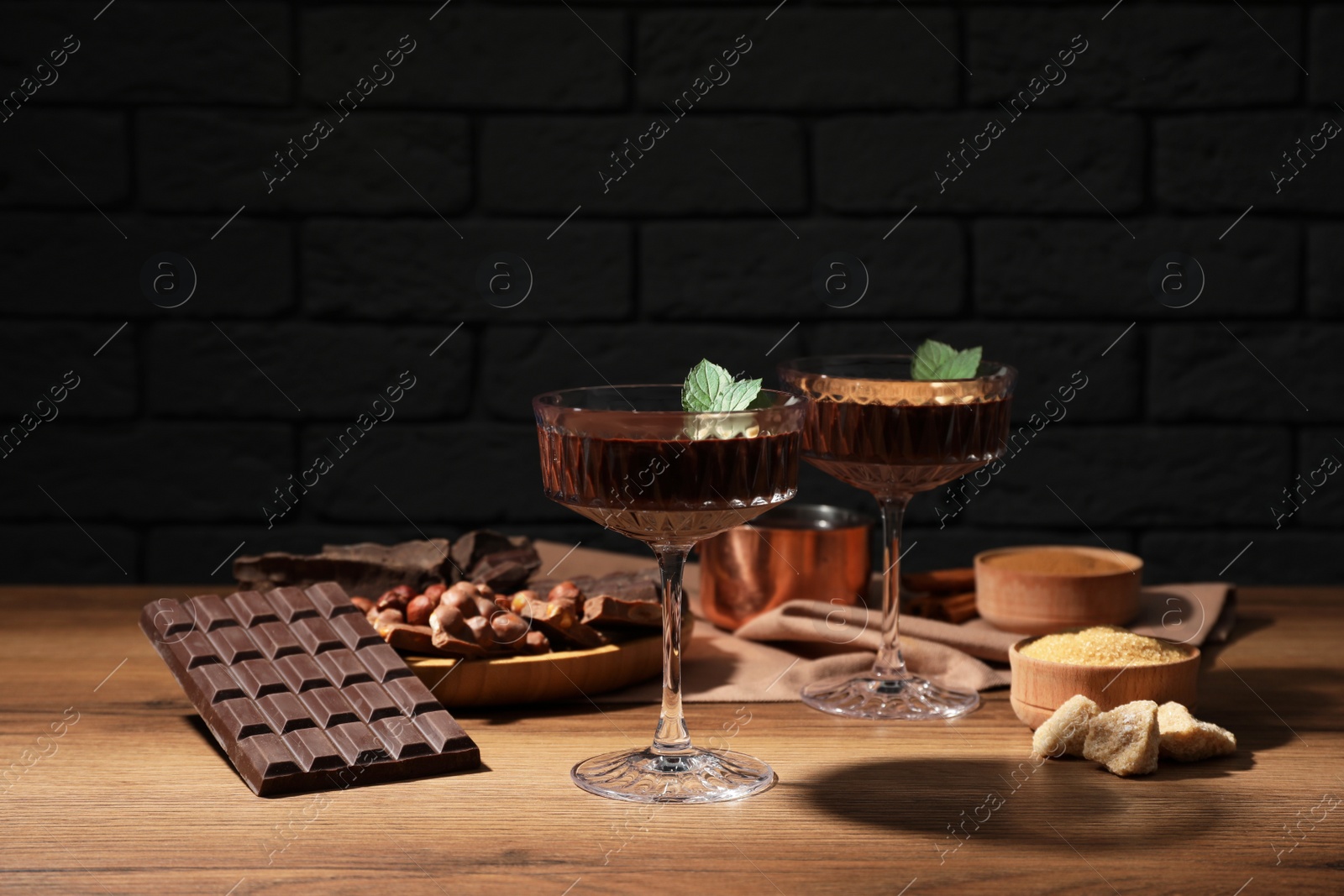 Photo of Dessert bowls of delicious hot chocolate and ingredients on wooden table