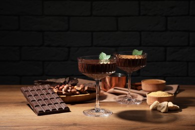 Dessert bowls of delicious hot chocolate and ingredients on wooden table