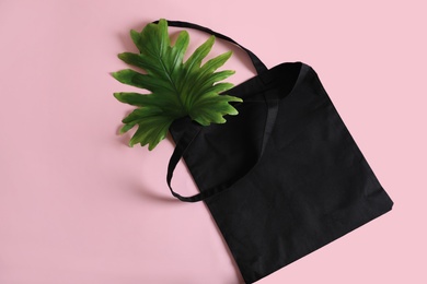 Photo of Eco tote bag and leaf on color background, top view. Space for design