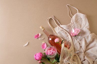 Flat lay composition with rose wine, mesh bag, dress and beautiful pink peonies on brown background. Space for text