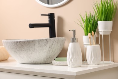 Different bath accessories and personal care products near sink on bathroom vanity