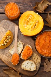 Photo of Slices of bread with delicious pumpkin jam and fresh pumpkin on wooden table, flat lay
