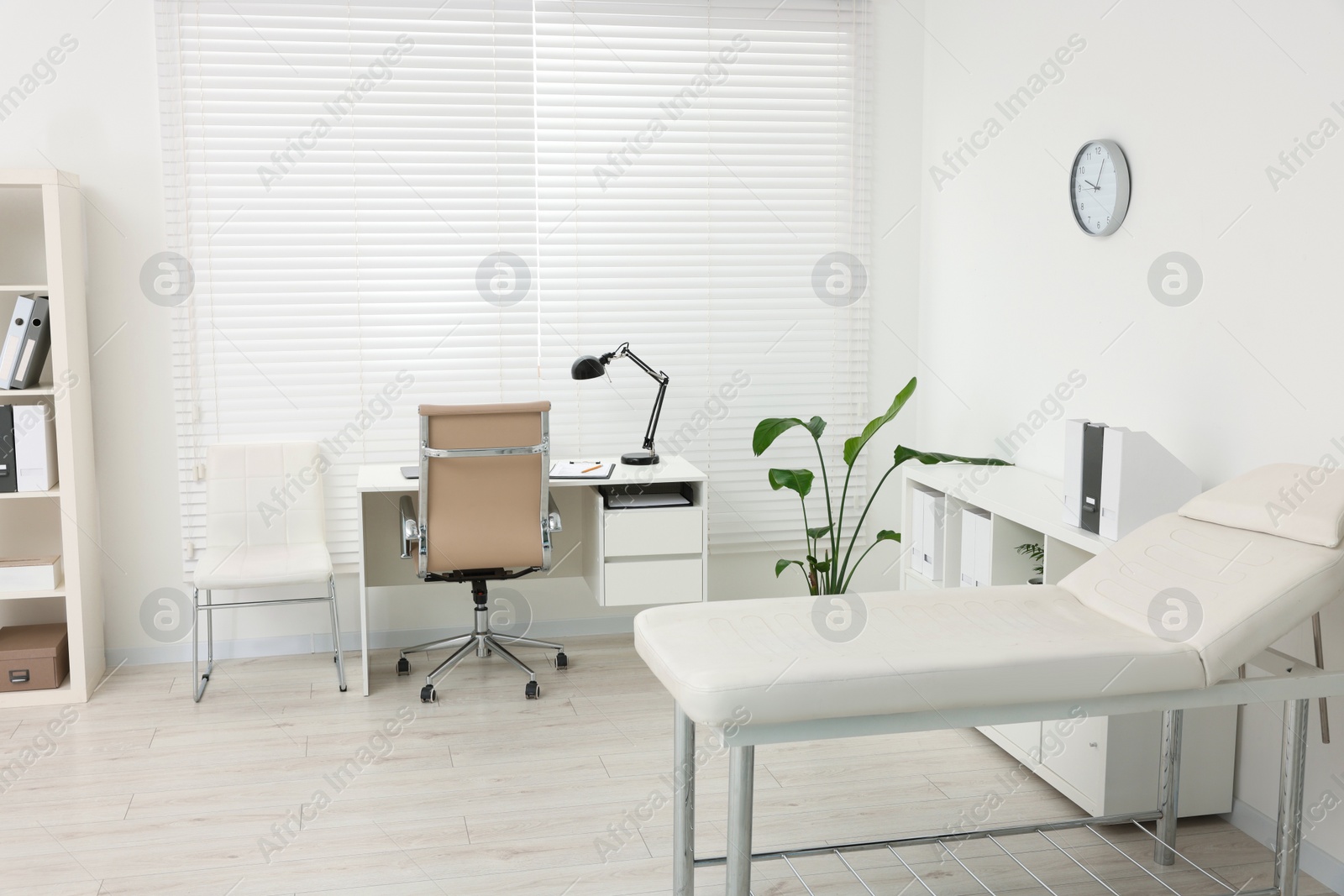 Photo of Modern medical office with doctor's workplace and examination table in clinic