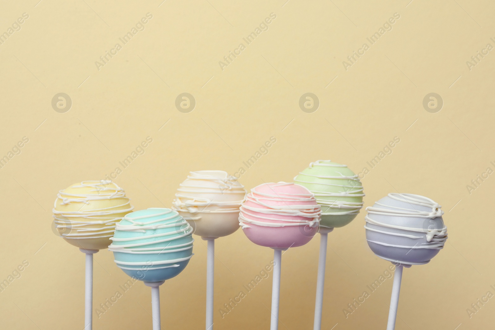 Photo of Sweet colorful cake pops on yellow background, space for text