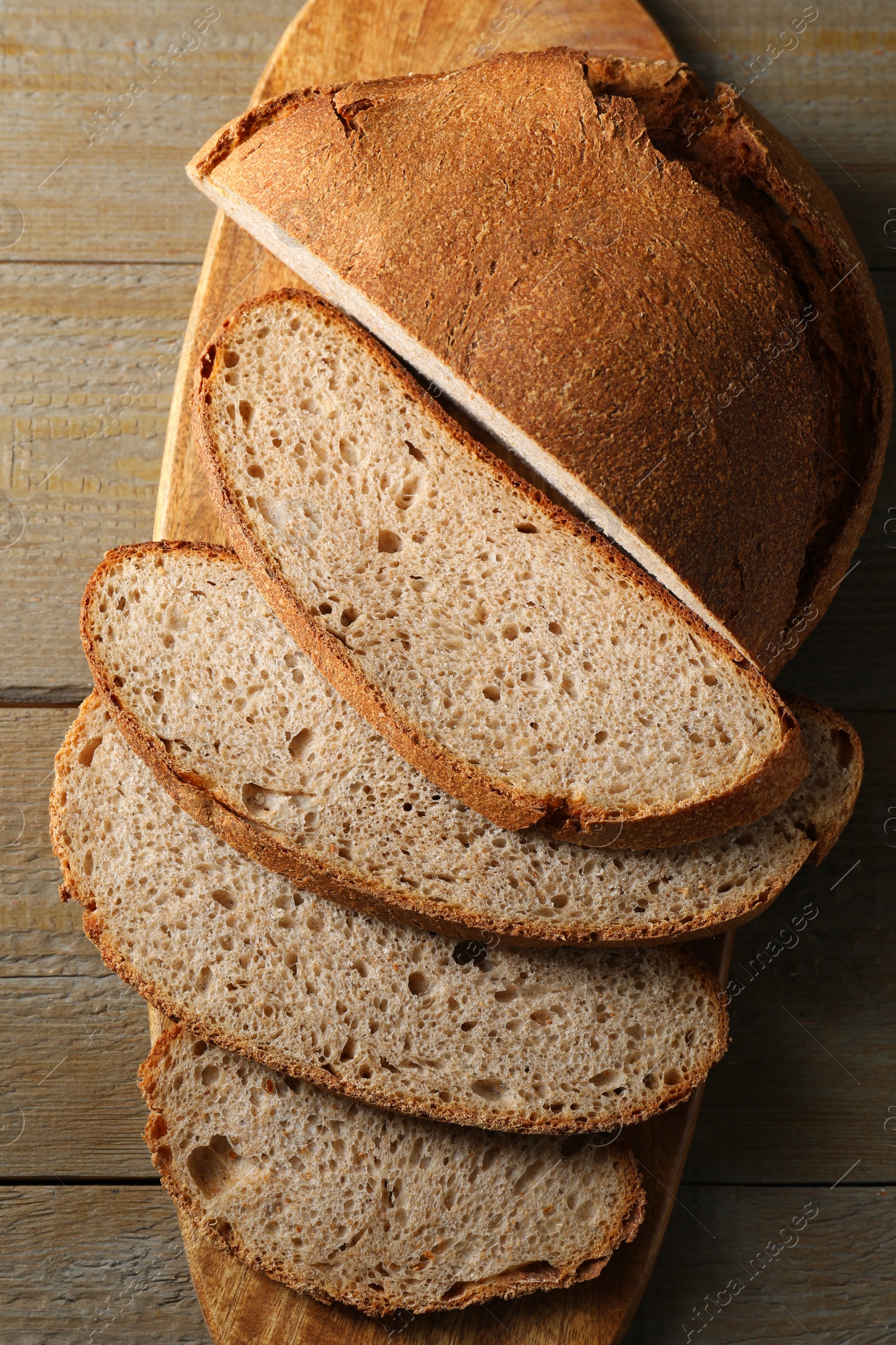 Photo of Freshly baked cut sourdough bread on wooden table, top view