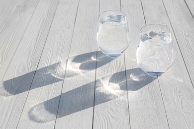 Glasses of refreshing drink with ice for hot summer day on wooden table. Space for text
