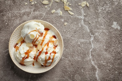 Photo of Tasty ice cream with caramel sauce in bowl on table, top view
