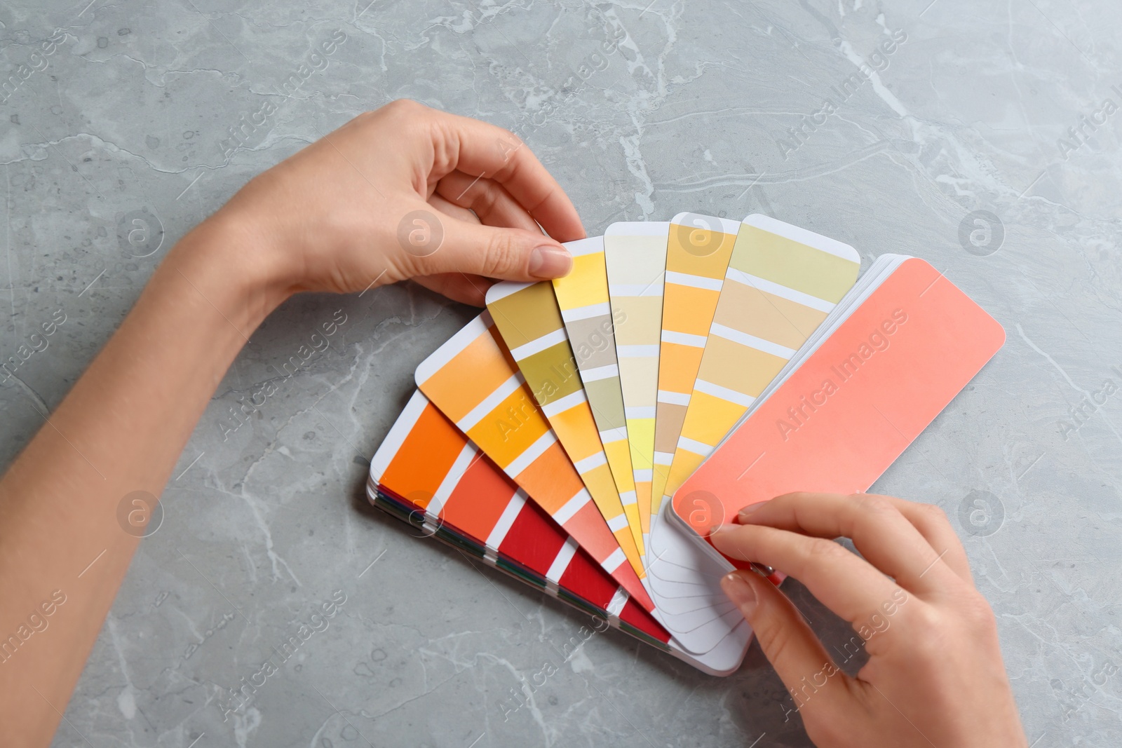 Photo of Woman with palette samples at grey marble table, top view