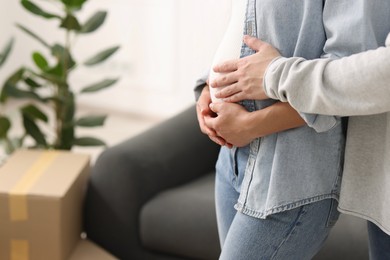 Photo of Pregnant woman and her husband in their new apartment, closeup. Space for text