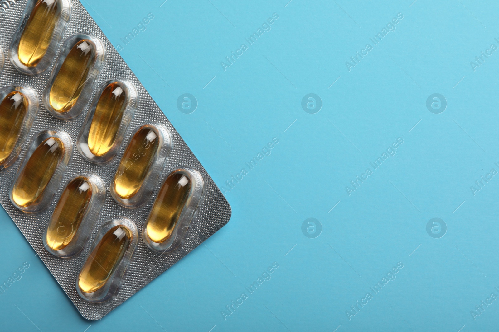 Photo of Dietary supplement capsules in blister pack on light blue background, top view. Space for text