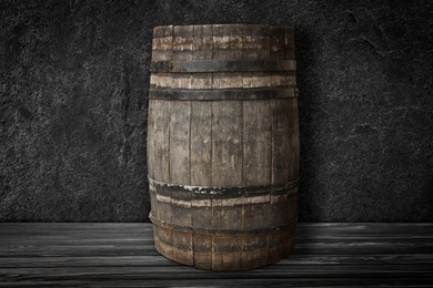 Image of One wooden barrel on black surface near dark textured wall