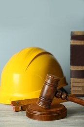 Photo of Construction and land law concepts. Judge gavel, protective helmet, ruler with books on wooden table