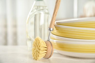 Photo of Cleaning brush for dish washing near bowls on white table indoors, closeup