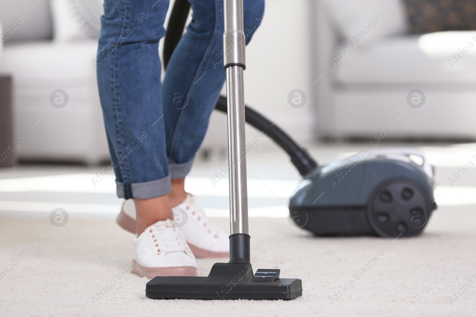 Photo of Woman cleaning carpet with vacuum cleaner, closeup