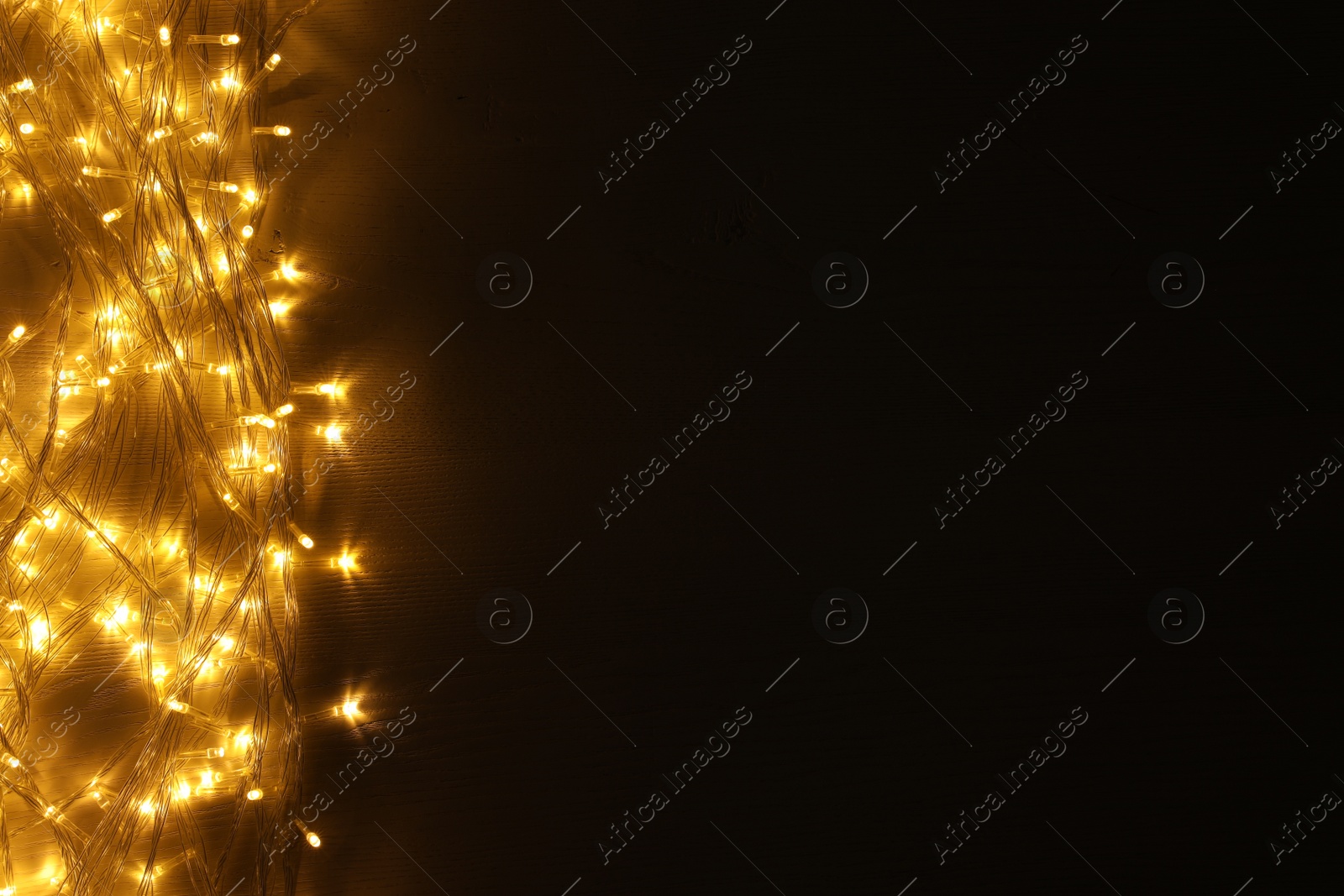 Photo of Beautiful glowing Christmas lights on wooden table, top view. Space for text